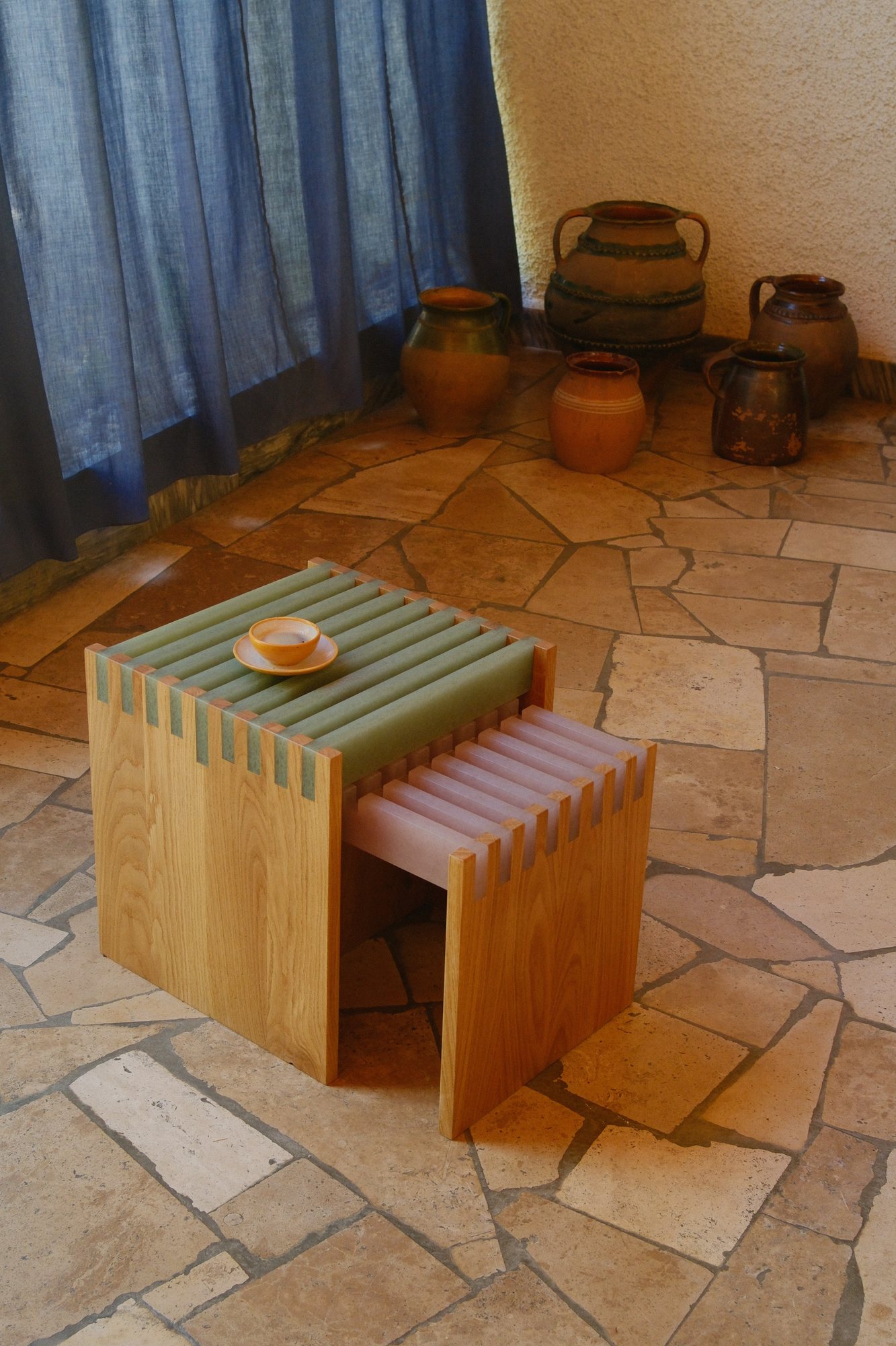 SML Cubes on a stone floor beside blue curtains