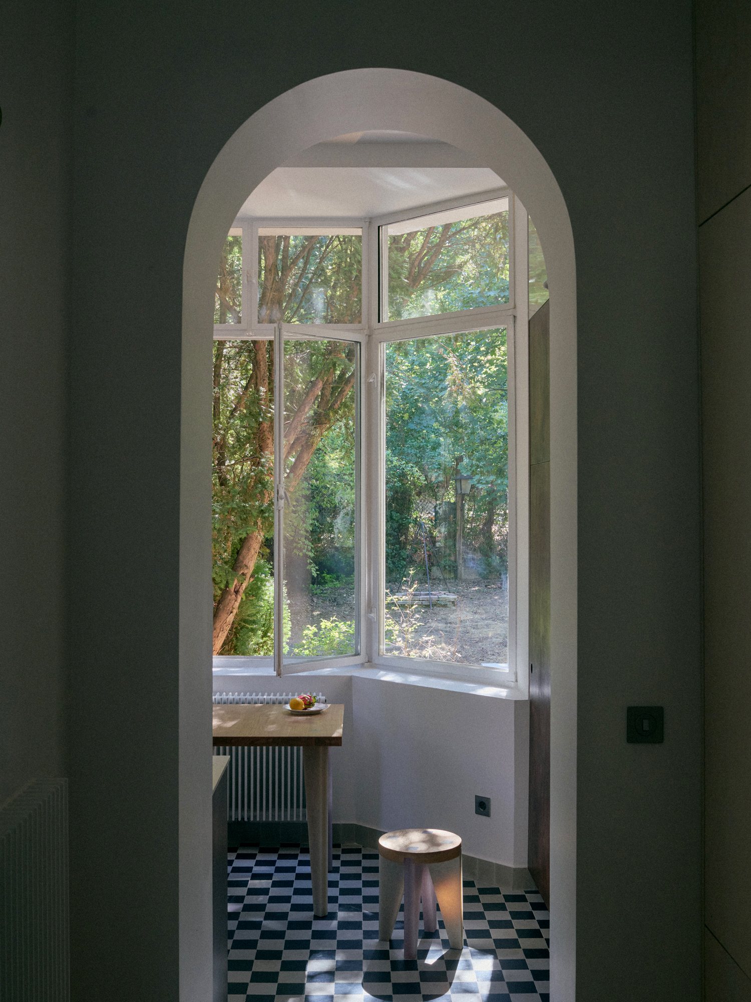 B6 apartment: arched doorway into a bay window room with a checkerboard floor