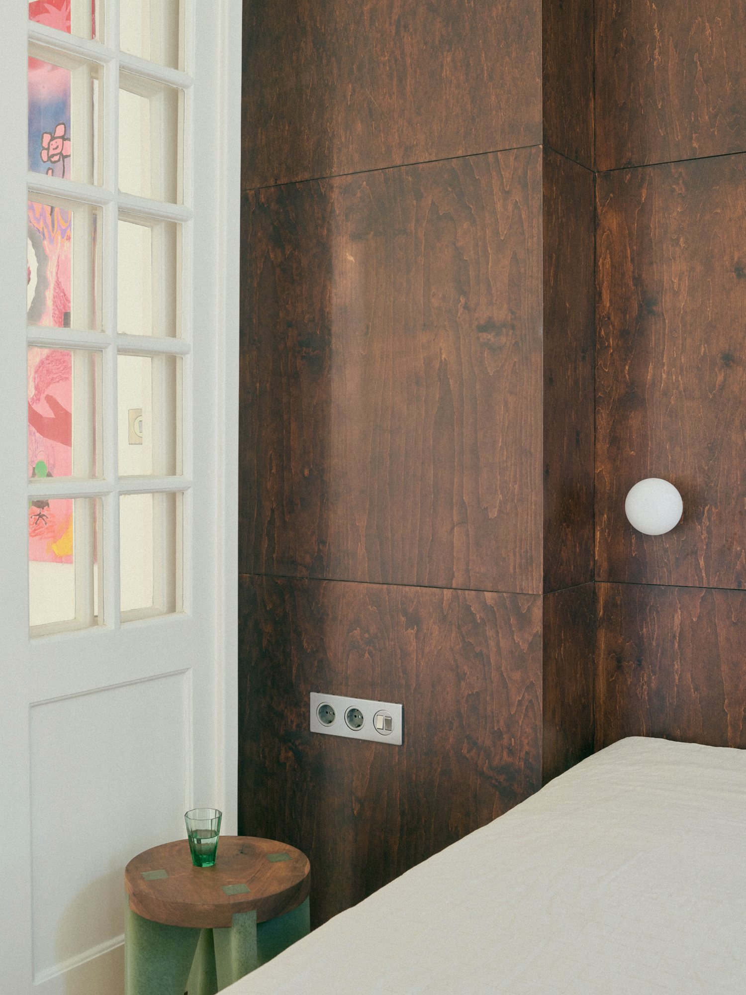 B6 apartment: dark oiled wood wall beside the bed