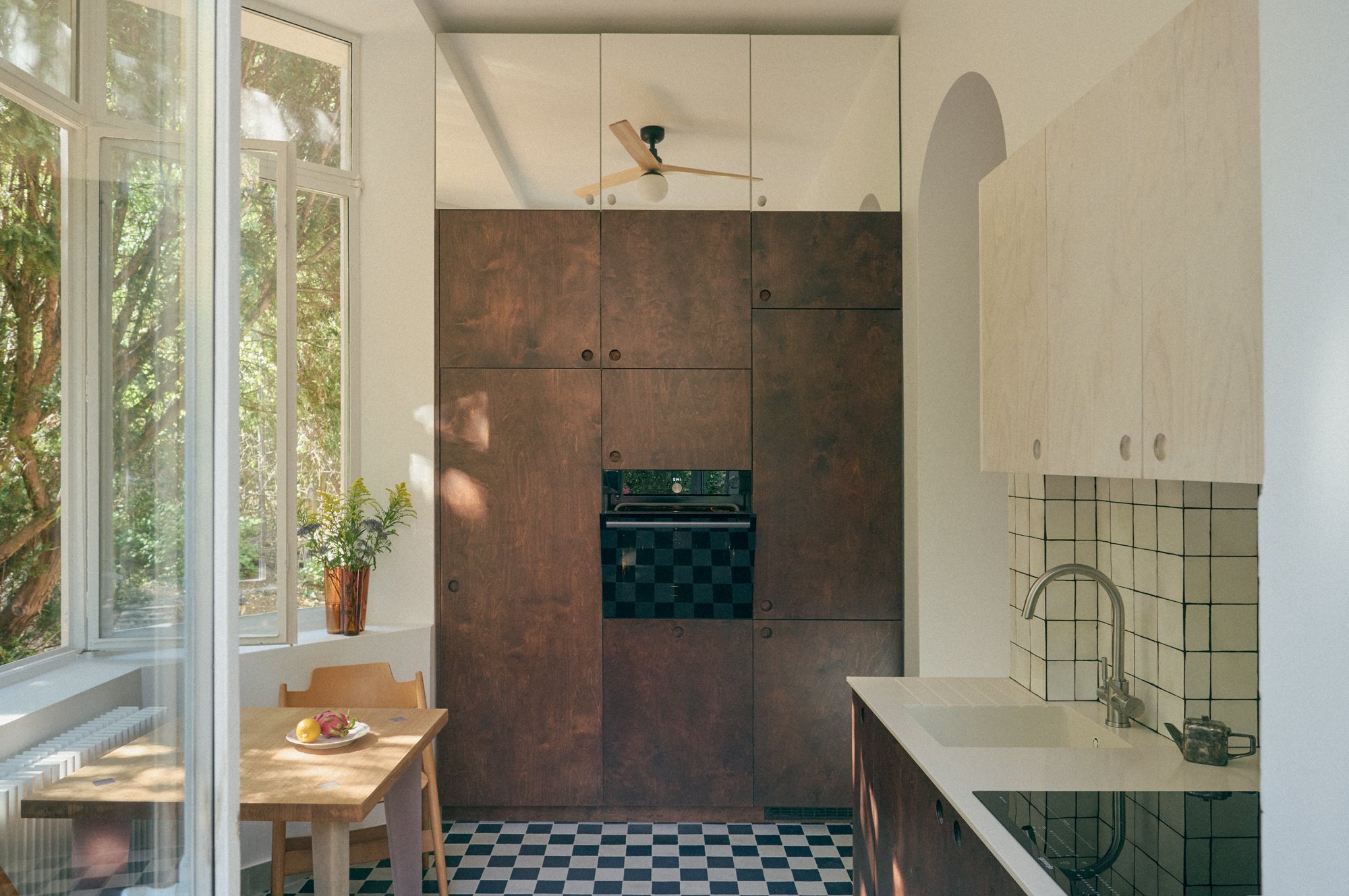 B6 apartment: dark oiled wood kitchen wall above a checkerboard floor