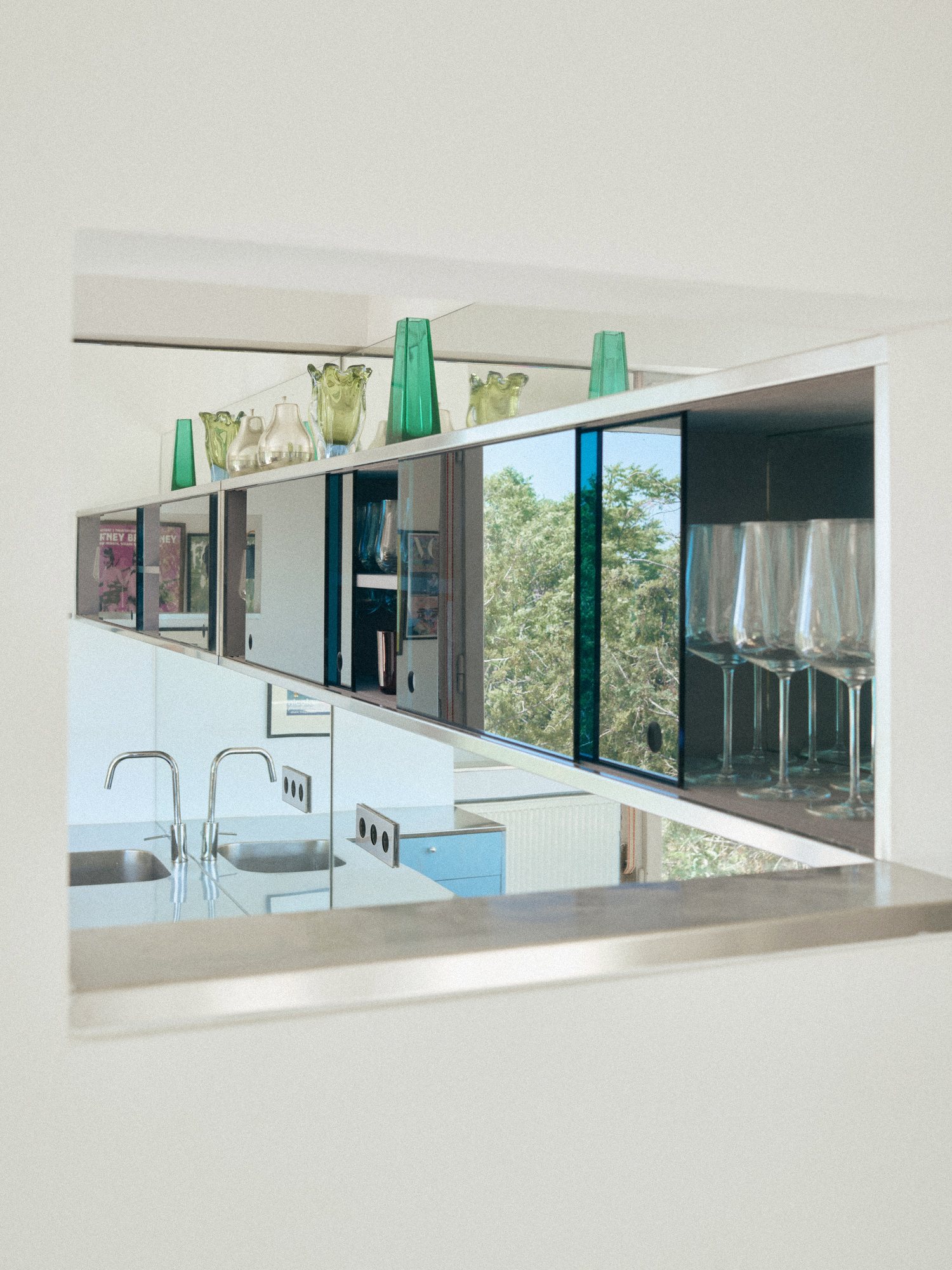 B75 kitchen: interior opening with the glassware collection reflected in stainless steel