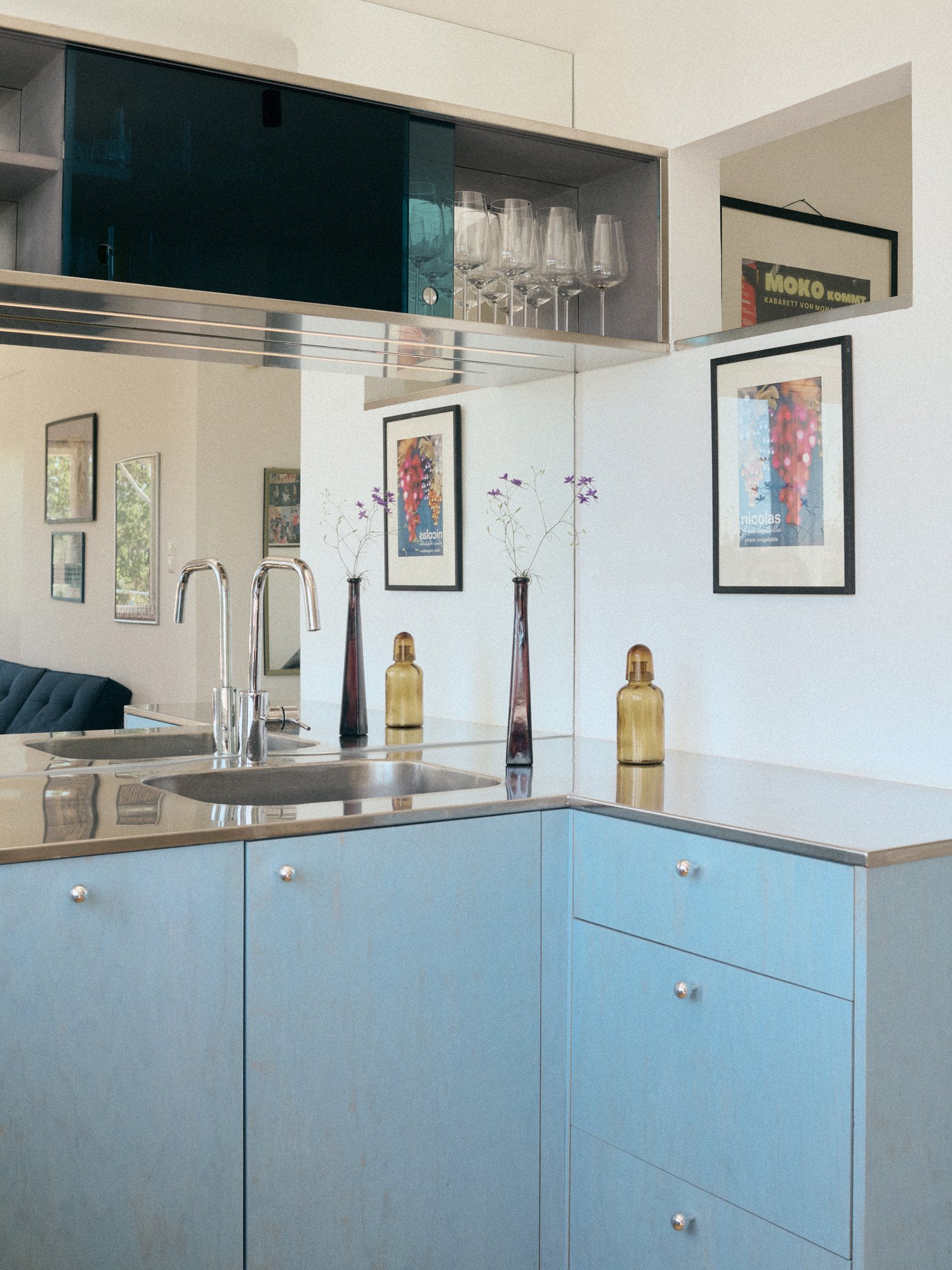 B75 kitchen: stainless steel sink, powder-blue cabinets and artworks