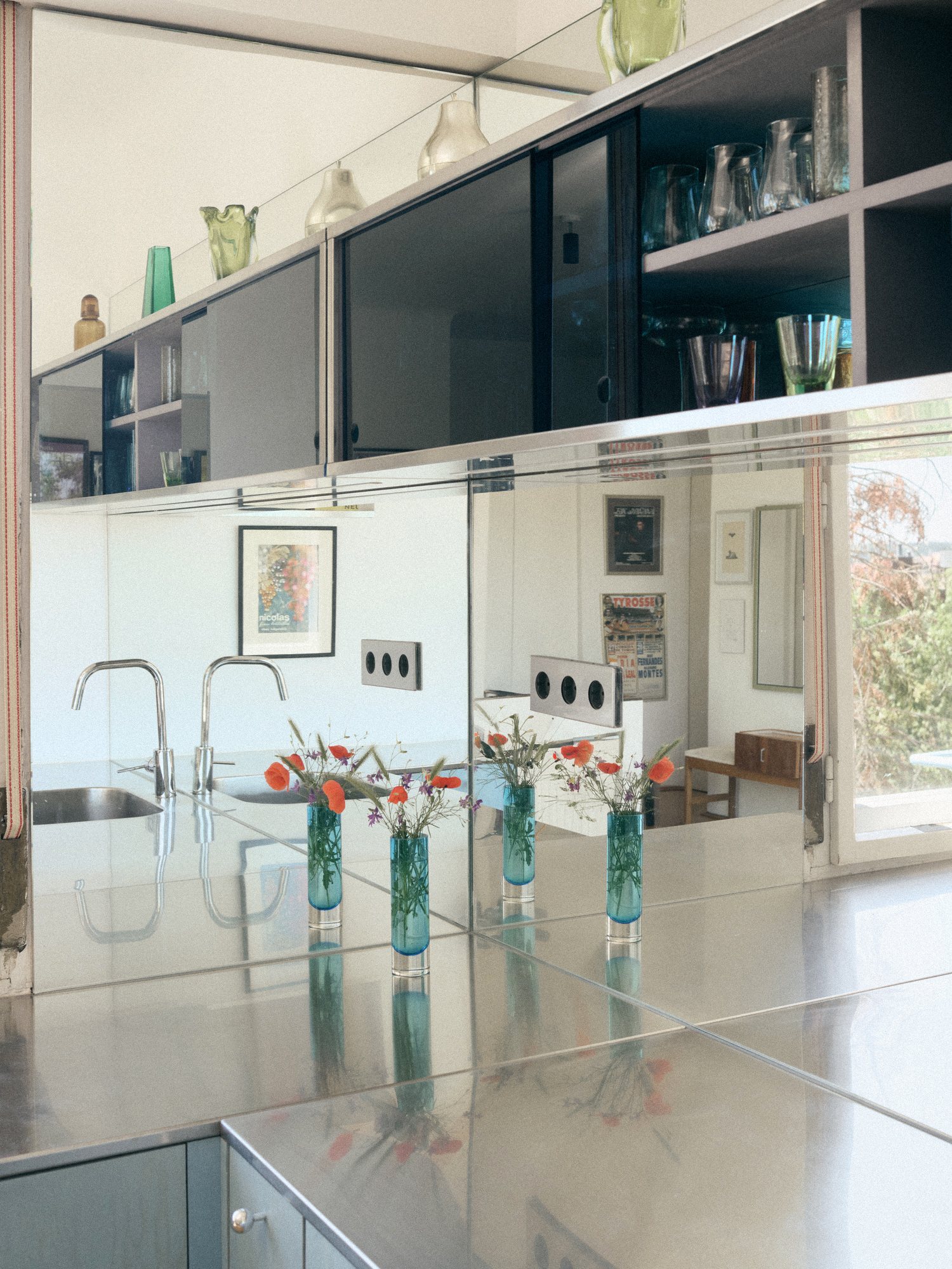 B75 kitchen: mirrored stainless steel worktop with flowers in glass vases
