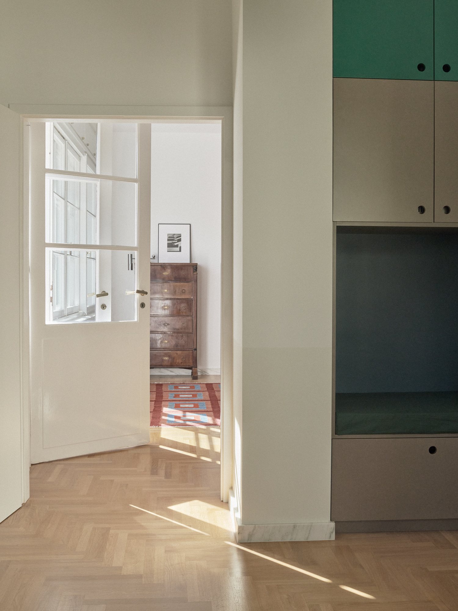 E6 apartment: doorway with herringbone parquet and built-in storage
