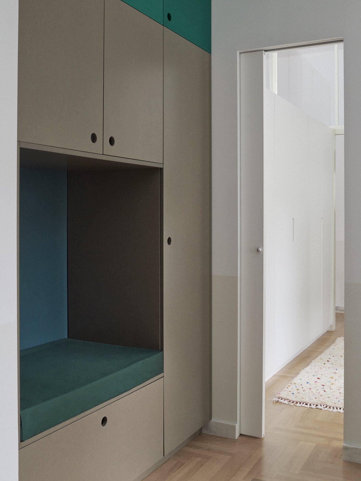 E6 apartment: built-in storage nook with a teal cushion