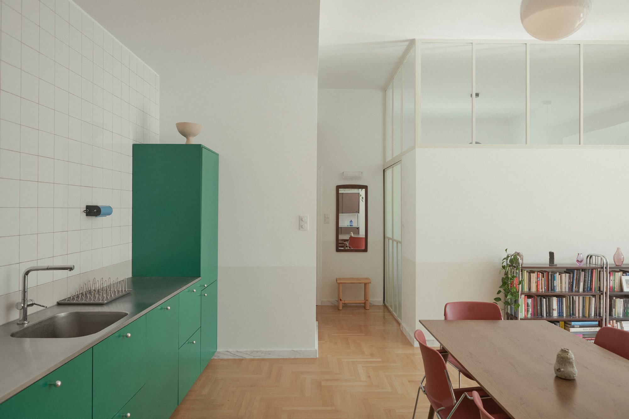 E6 apartment: green kitchen opening onto the dining area