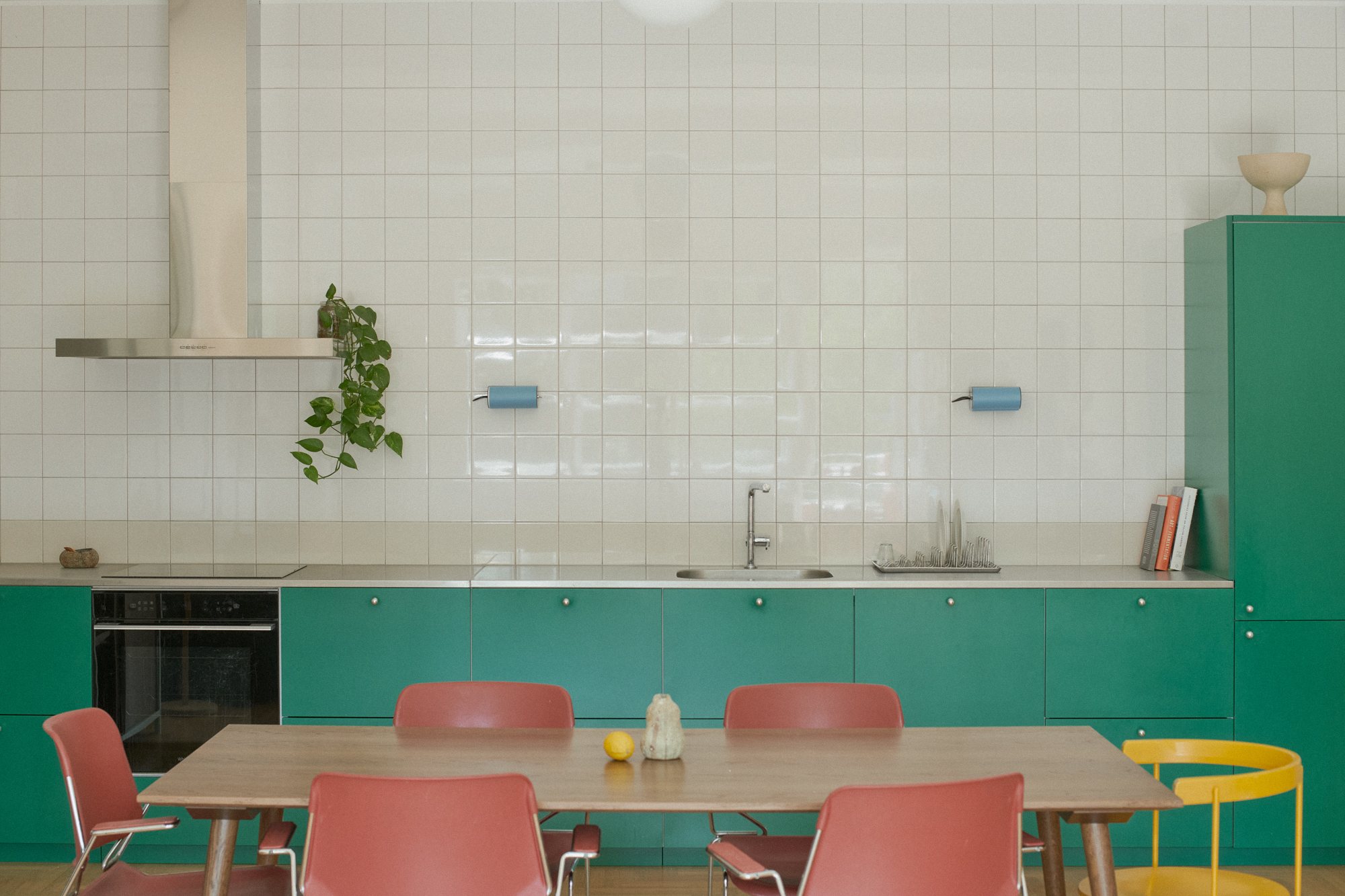 E6 apartment: open-plan kitchen with green Valchromat cabinetry and a dining table