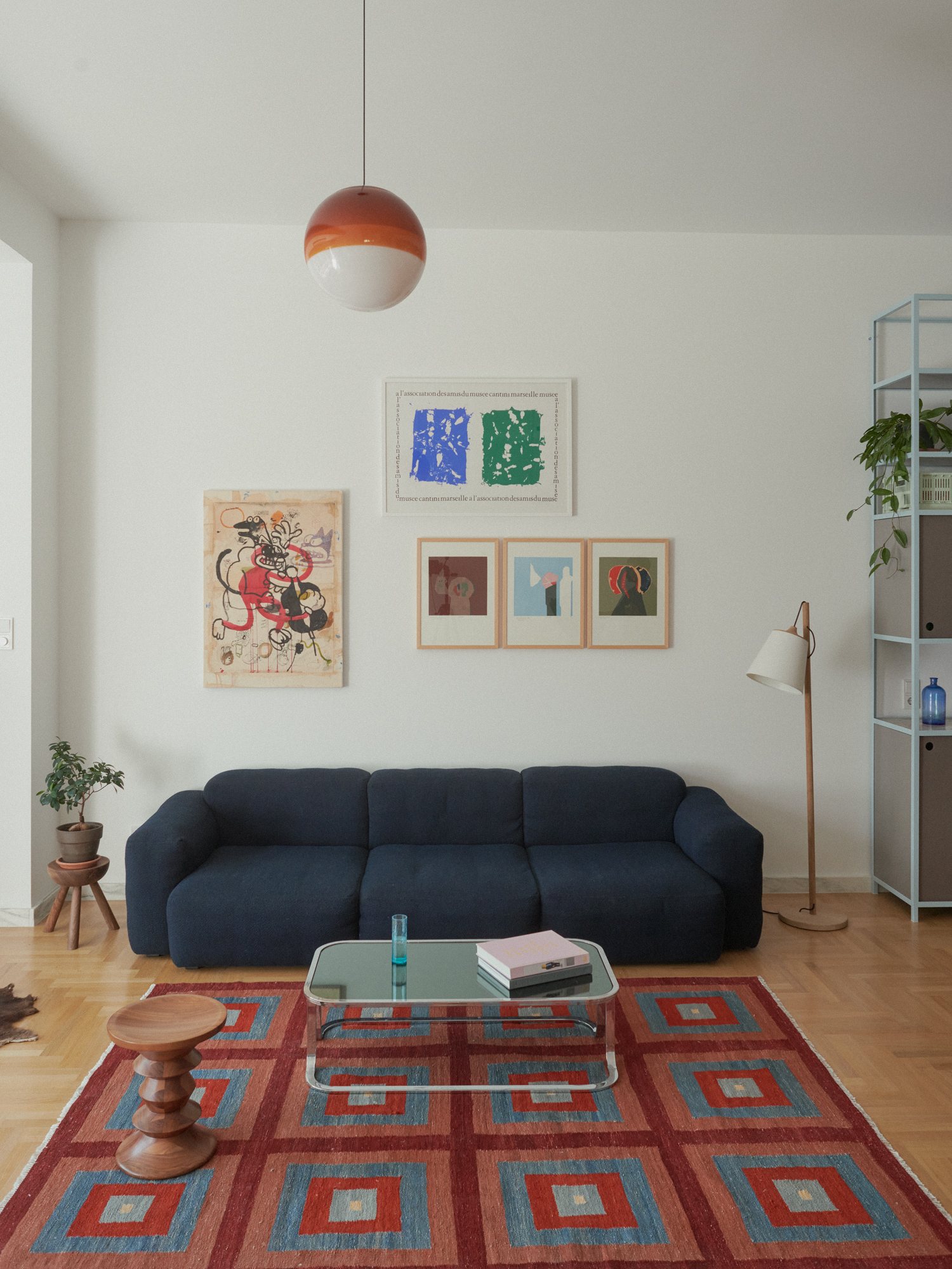 E6 apartment: navy sofa, red rug and framed artworks