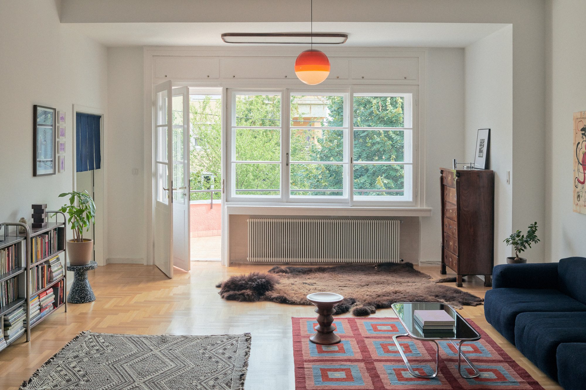 E6 apartment: living room with tall windows, patterned rugs and a blue sofa